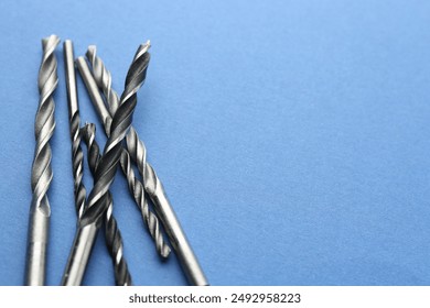 Many different drill bits on light blue background, space for text