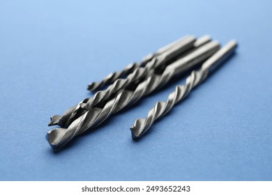 Many different drill bits on light blue background, closeup