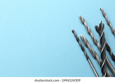 Many different drill bits on light blue background, top view. Space for text