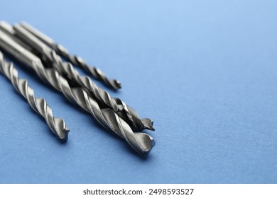 Many different drill bits on light blue background, closeup. Space for text