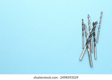 Many different drill bits on light blue background, top view. Space for text