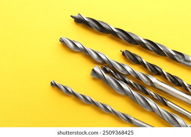 Many different drill bits on yellow background, top view