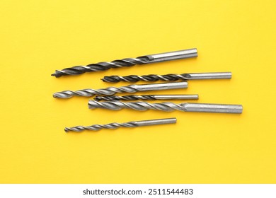 Many different drill bits on yellow background, top view