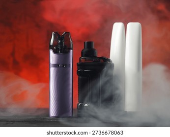 many different electronic cigarettes on a smoky background. Disposable and refillable smoking devices