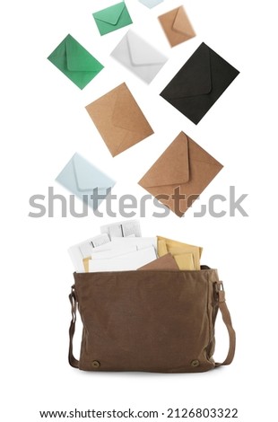 Many different envelopes falling into brown postman's bag on white background