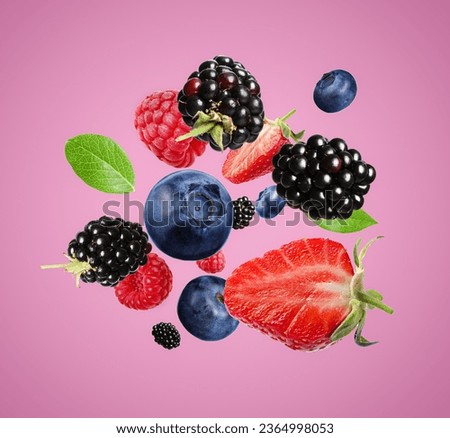 Many different fresh berries falling on hot pink background