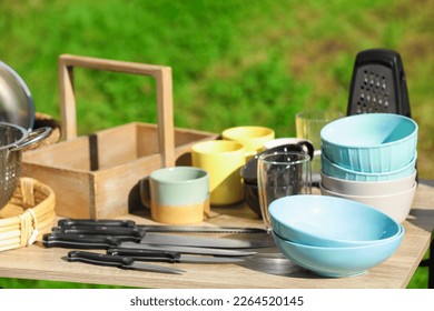 Many different items for kitchen on wooden table outdoors. Garage sale