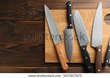 Many different knives and board on wooden table, top view. Space for text