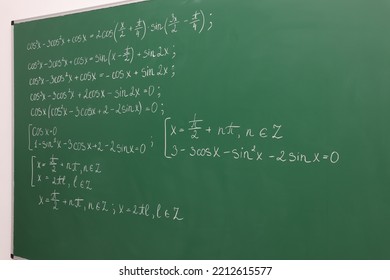 Many different math formulas written on green chalkboard