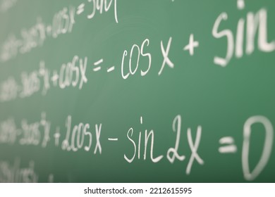 Many different math formulas written on green chalkboard, closeup