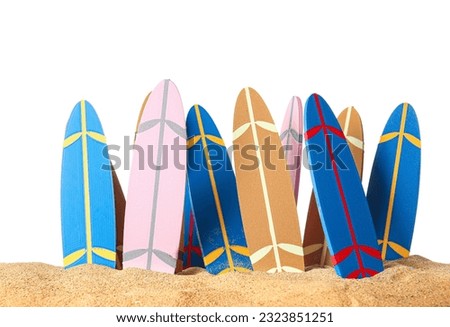 Many different mini surfboards on sand against white background