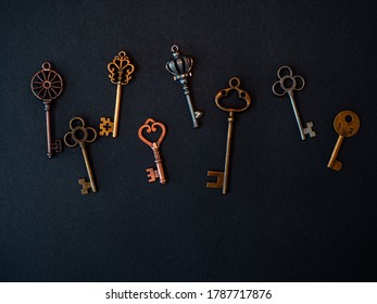 Many different old keys from different locks, scattered chaotically, flat lay. Finding the right key, encryption, concept. Retro vintage copper keys in black background