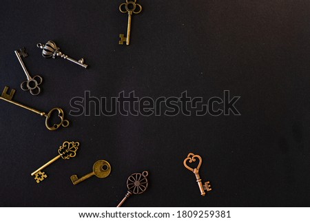 Many different old keys from different locks, scattered chaotically, flat lay. Finding the right key, encryption, concept. Retro vintage brass keys on a black background, copy space in the center