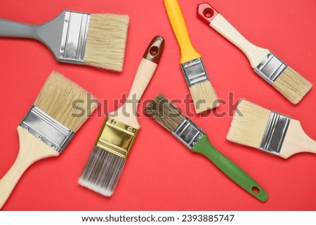 Many different paint brushes on red background, flat lay