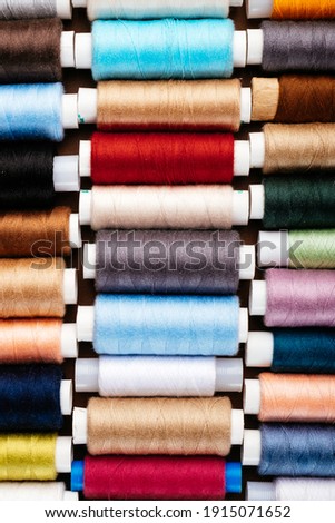 Many different reels with threads, flat lay, top view. Colored threads, close-up, bright background. Cutting and sewing clothes concept. Accessories for needlework.