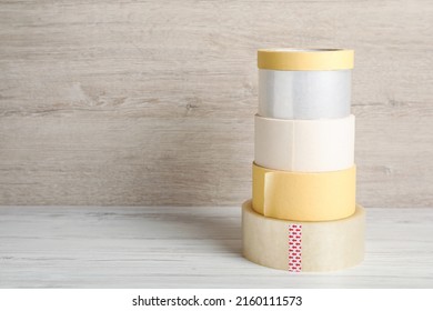 Many different rolls of adhesive tape on wooden table. Space for text - Shutterstock ID 2160111573
