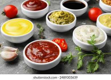 Many different sauces and spices on grey table, closeup