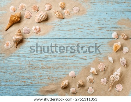 Many different seashells and beach sand, on a blu wooden background, copy space for text. Seashells on beach sand,top view with copy space.