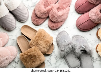 Many different soft slippers on white marble background, flat lay