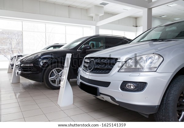 Many different used cars are in the dealership\
of a dealer accepted by the trade-in system during a sale in a\
bright room with large\
windows.