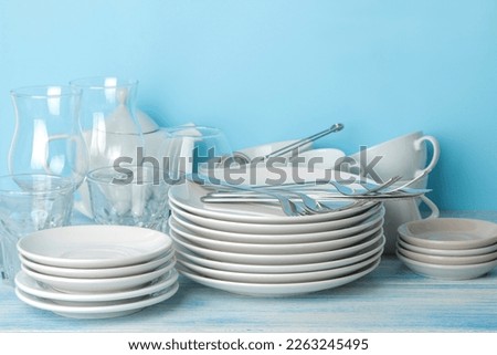 many different utensils. Tableware on a blue background. Clean tableware. various plates, bowls and cups.