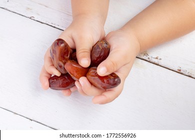 Many Dried Date Fruits In Kids Palms. Hands Holding Dates