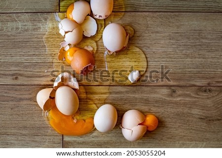 Many eggs fall down to the floor and broken. An accident in the kitchen. 