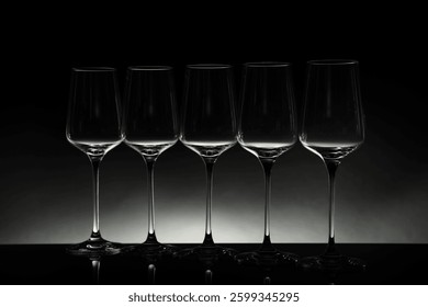 Many empty clean glasses on mirror surface against black background
