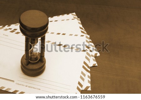 Many envelopes with hourglass on table, delivering time aconcept