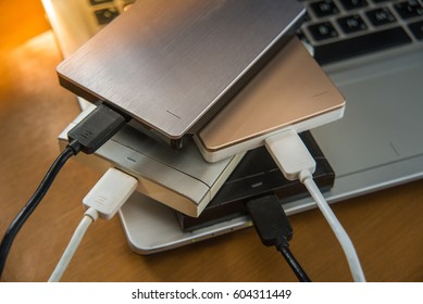 Many external hard disk on laptop  for backup files and important information using USB 3.0 connection, wooden table background.