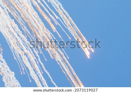 Many falling burning lights from the explosion in the blue sky leave a plume of smoke