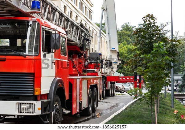 Many fire engine\
trucks with ladder and safety equipment at accident in highrise\
tower residential apartment or office building in city center.\
Emergency rescue at\
disaster