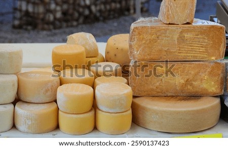 Many forms of fresh and aged cheese of various sizes for sale at the local market stall in Europe