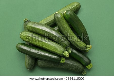 Many fresh zucchini on green background