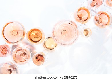 Many glasses of rose wine at wine tasting. Concept of rose wine and variety. White background. Top view, flat lay design. Horizontal. Living Coral Pantone color of the year 2019 shade