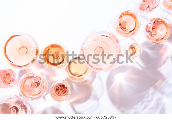 Many glasses of rose wine at wine tasting. Concept\
of rose wine and variety. White background. Top view, flat lay\
design. Direct sunlight. Toned image. Living Coral Pantone color of\
the year 2019