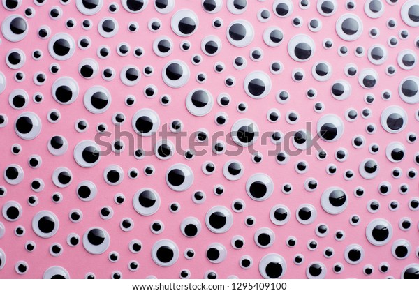Many googly\
eyes organized over pink\
background