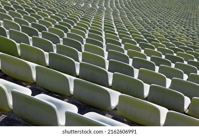 many green empty seats in the bleachers of stadium without people