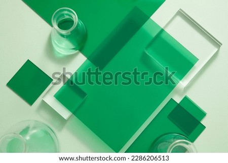 Many green plastic board are displayed with some erlenmeyer flask containing green fluid and square transparent podium. Science laboratory research and development concept.