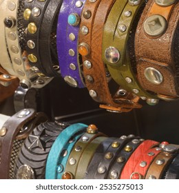 Many handmade leather bracelets and belts with various metal studs are for sale in the leather goods store - Powered by Shutterstock