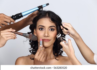 Many Hands Helping Tan Skin Woman Curl Black Hair To Be More Beautiful With Brush, Eye Curler, Lipstick, Hair Dresser, Studio Lighting Gray Background