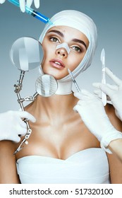 Many hands holding medical instruments near face patient. Nurses holding magnifying glass, scalpel, syringe near her face. Plastic Surgery concept