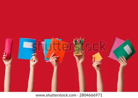 Many hands with notebooks, pencil case and stationery on red background