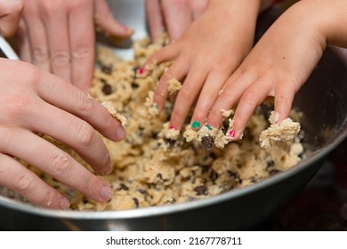 Many hands in the pot making cookie dough with a shallow depth of field