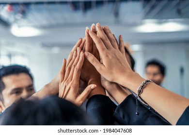Many happy business people raise hands together with joy and success. Company employee celebrate after finishing successful work project. Corporate partnership and achievement concept.