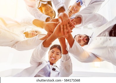 Many happy doctors stack hands together as team for motivation
