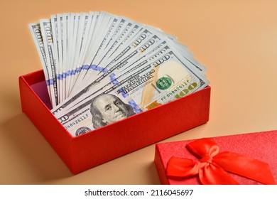 Many hundred dollar bills in a gift box