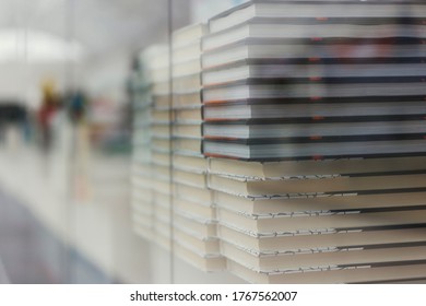 Many Identical Books Are Stacked On Top Of Each Other In A Glass Display Case Of A Bookstore.