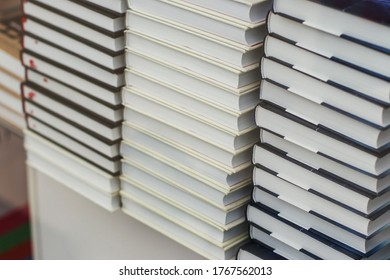 Many Identical Books Are Stacked On Top Of Each Other In A Glass Display Case Of A Bookstore.