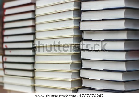 Many identical books are stacked on top of each other in a glass display case of a bookstore.